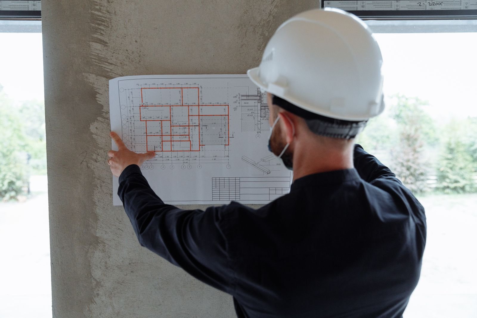 Ingénieur en structure, casque de chantier sur la tête, qui consulte les plans avant le début des travaux, projet de rénovation à Montréal