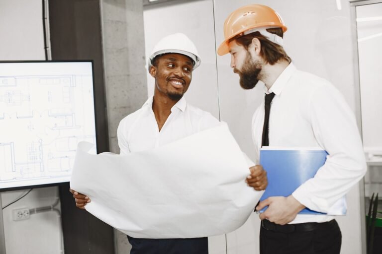 Deux professionnels en casque de chantier qui révisent les plans d’un projet avant la soumission, entrepreneur général à Montréal